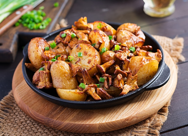 Baked potatoes with garlic, herbs and fried chanterelles in a cast iron skillet.