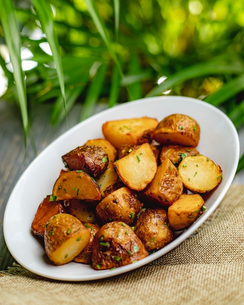 Foto gratuita patate al forno con erbe in un piatto bianco