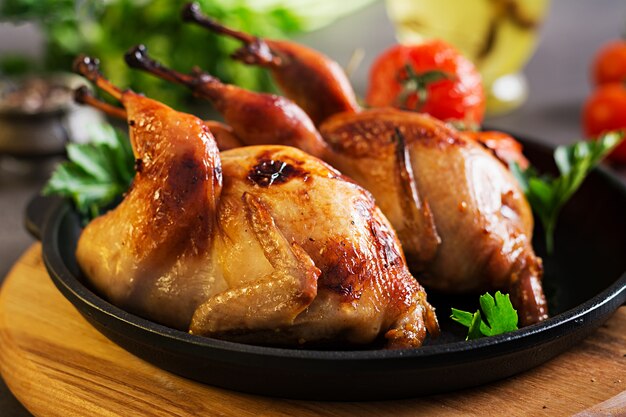 Baked quails in pan on a dark surface