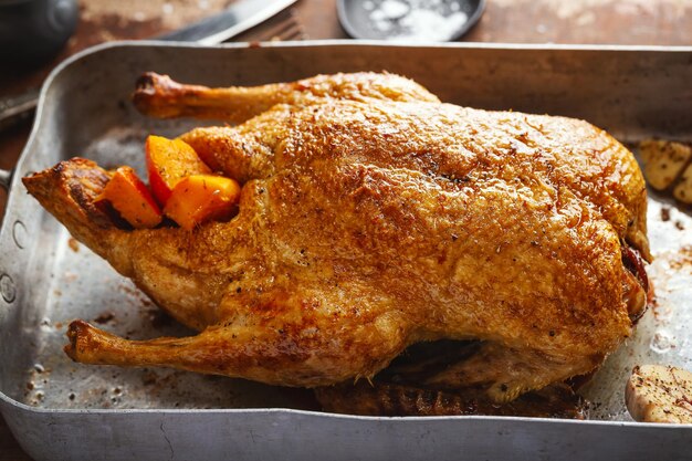 Baked roasted duck with vegetables on pan on old wooden background. Closeup