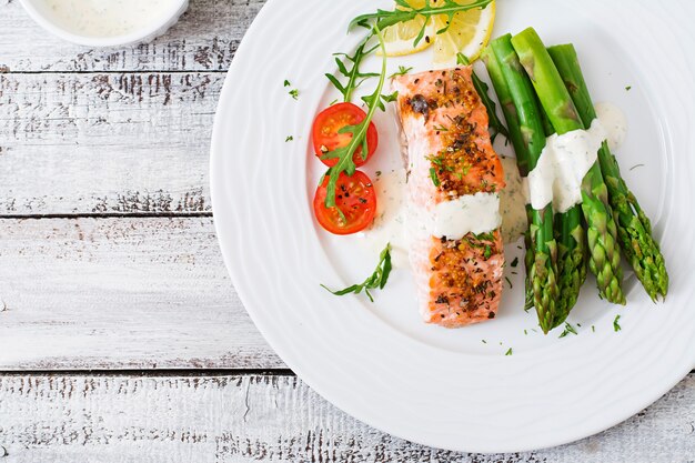 Baked salmon garnished with asparagus and tomatoes with herbs. Top view