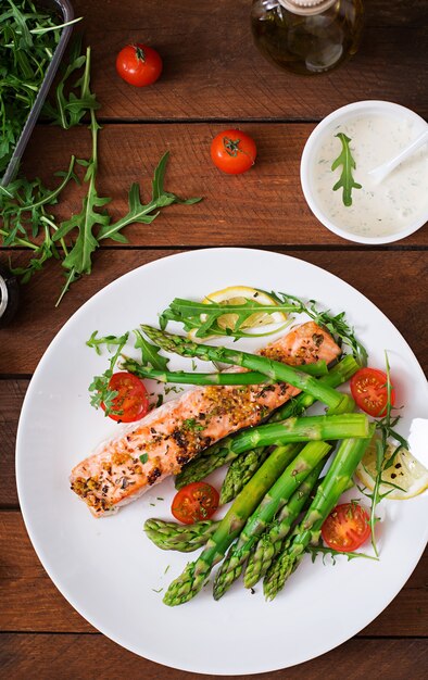 Baked salmon garnished with asparagus and tomatoes with herbs.