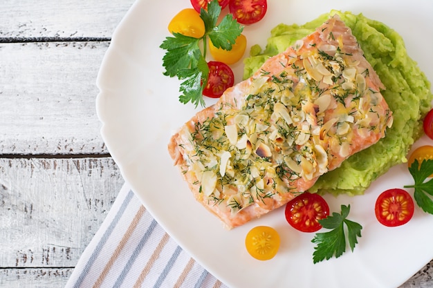 Free photo baked salmon with cheese and almond crust and garnished with mashed potatoes and green peas