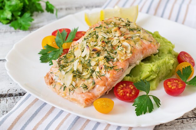 Baked salmon with cheese and almond crust and garnished with mashed potatoes and green peas