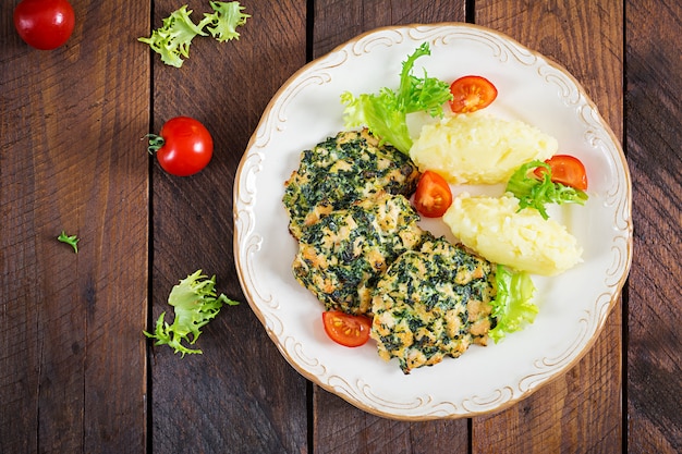 Baked steak chopped chicken fillet with spinach and a side dish of mashed potatoes.