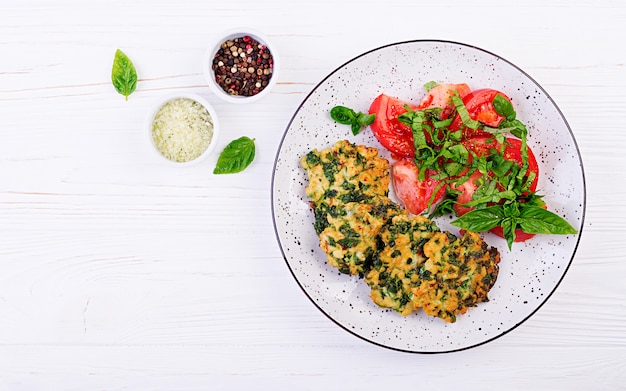 Baked steak chopped chicken fillet with spinach and a side dish of tomatoes salad. European cuisine. Dietary food. Top view