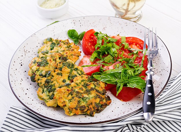 Baked steak chopped chicken fillet with spinach and a side dish of tomatoes salad. European cuisine. Dietary food.