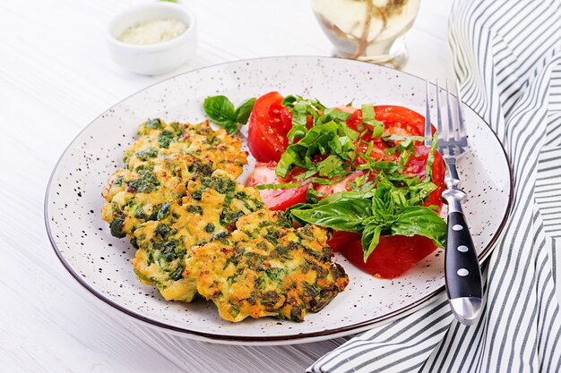 Baked steak chopped chicken fillet with spinach and a side dish of tomatoes salad. European cuisine. Dietary food.