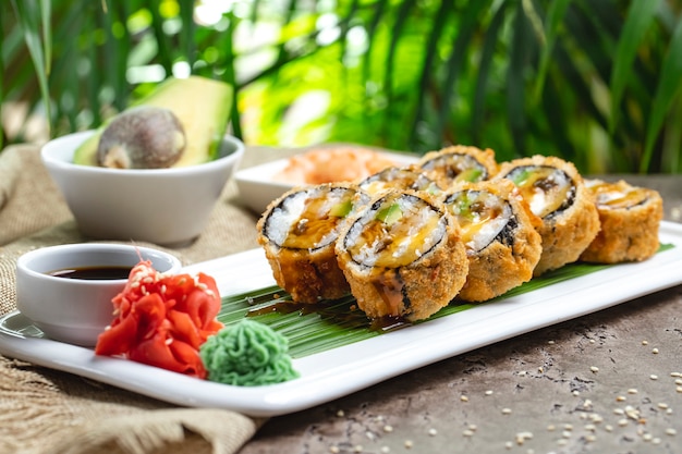 Free photo baked sushi with wasabi, ginger and soy sauce on a bamboo leaf