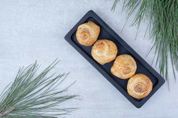 Foto gratuita panini dolci al forno su banda nera con ramo di pino. foto di alta qualità