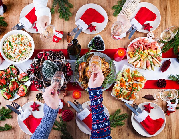 구운 칠면조. 크리스마스 저녁. 크리스마스 테이블에는 밝은 색과 양초로 장식 된 칠면조가 제공됩니다. 프라이드 치킨, 테이블. 가족 식사. 상위 뷰, 프레임에 손