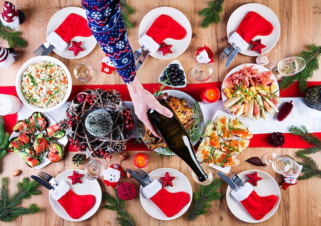 Baked turkey. Christmas dinner. The Christmas table is served with a turkey, decorated with bright tinsel and candles. Fried chicken, table.  Family dinner. Top view, hands in the frame