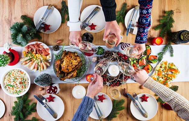 구운 칠면조. 크리스마스 저녁. 크리스마스 테이블에는 밝은 색과 양초로 장식 된 칠면조가 제공됩니다. 프라이드 치킨, 테이블. 가족 식사. 상위 뷰, 프레임에 손