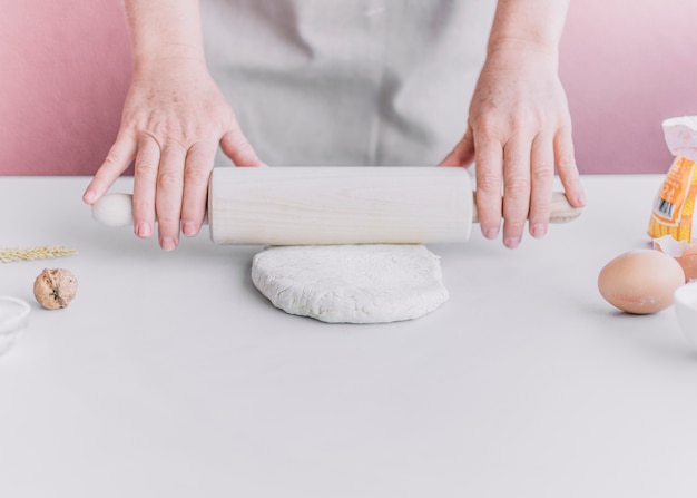 Foto gratuita panettiere che appiattisce la pasta con il mattarello