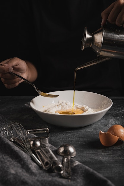 Baker hands pouring oil in dough composition