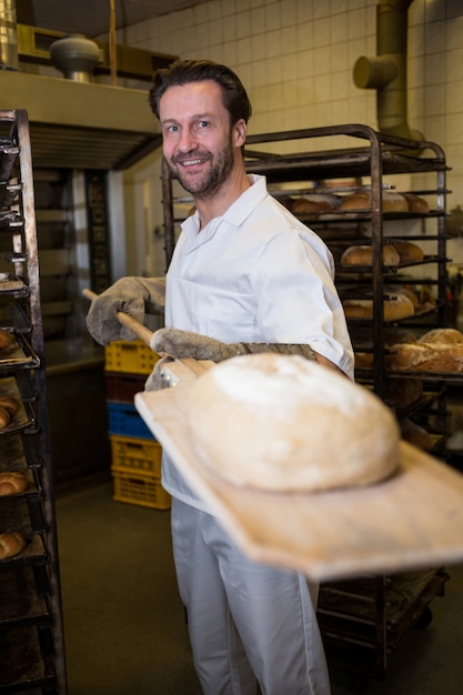 Foto gratuita baker, detiene il panino cotto in cucchiaio di legno