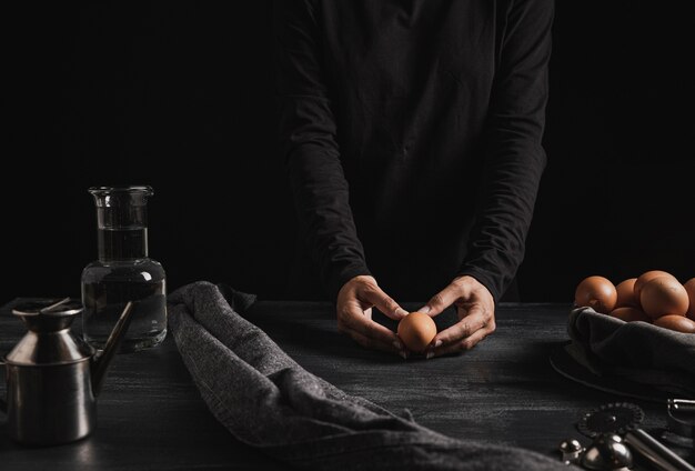 Baker holding egg on kitchen top