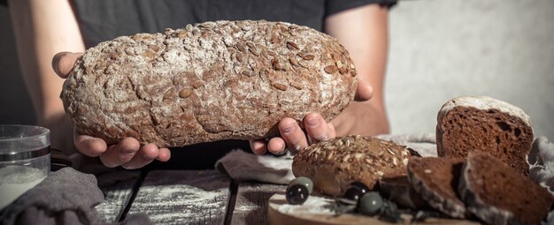 пекарь держит в руках свежий хлеб