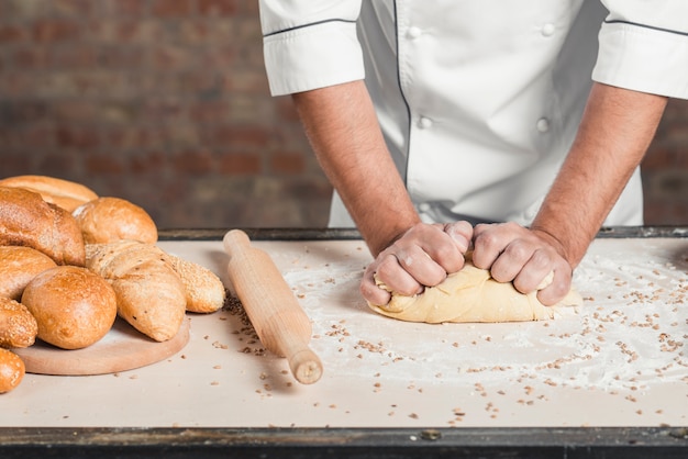 Baker kneading the dough on counter