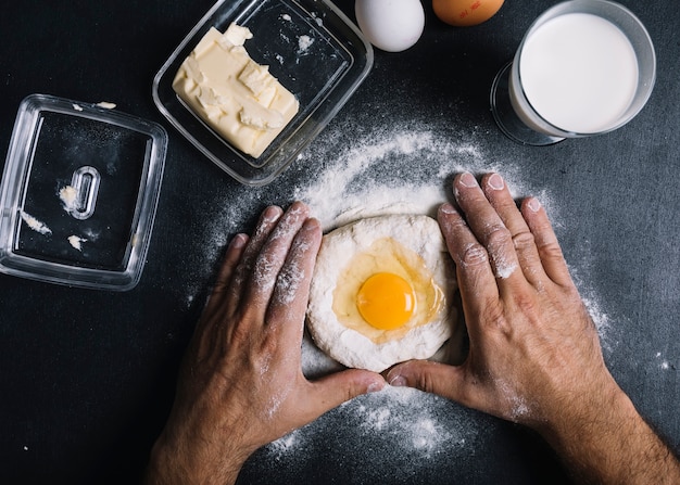 Baker kneading dough with egg york on kitchen counter