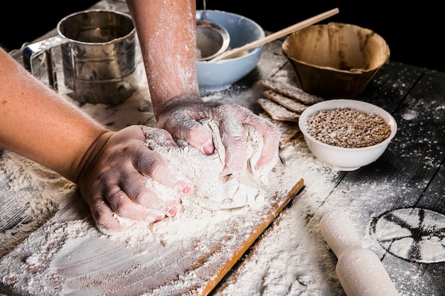 Baker kneading the dough with flour over the kitchen table