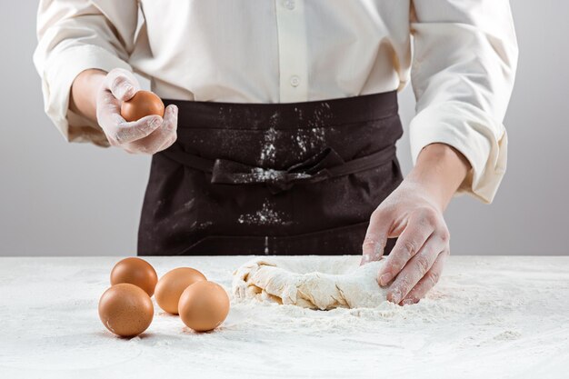 The baker making bread, male hands, kneading a dough, cooking coat