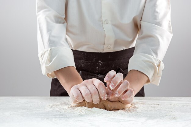 Пекарь делает хлеб, мужские руки, замешивает тесто, готовит пальто