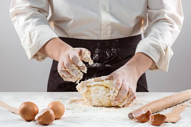 The baker making bread, male hands, kneading a dough, cooking coat