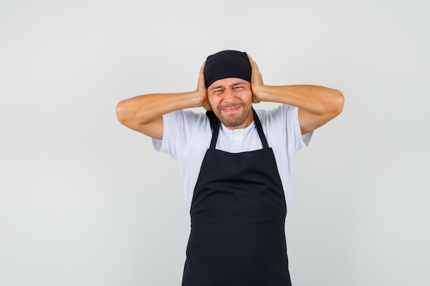 Baker man clasping head in hands in t-shirt