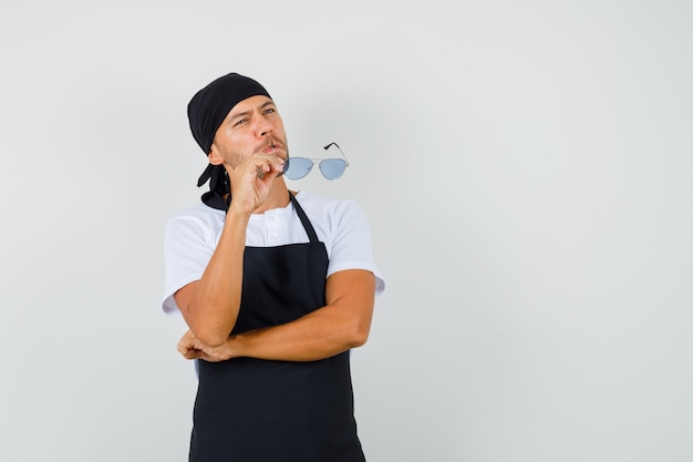 Baker man holding glasses while looking up in t-shirt