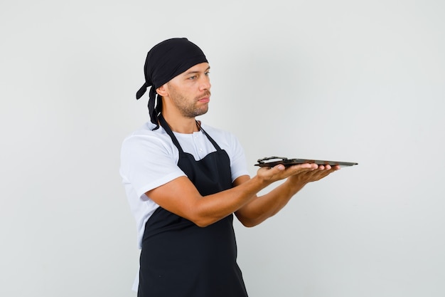 Baker man holding metallic tray in t-shirt