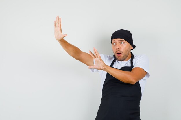 Baker man raising palms to defend himself in t-shirt