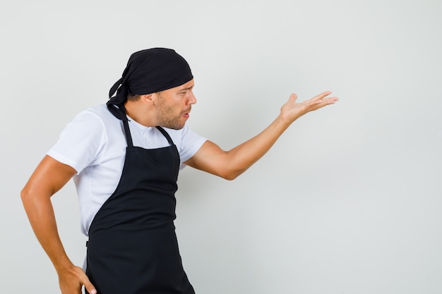 Baker man in t-shirt, apron making asking question gesture and looking angry