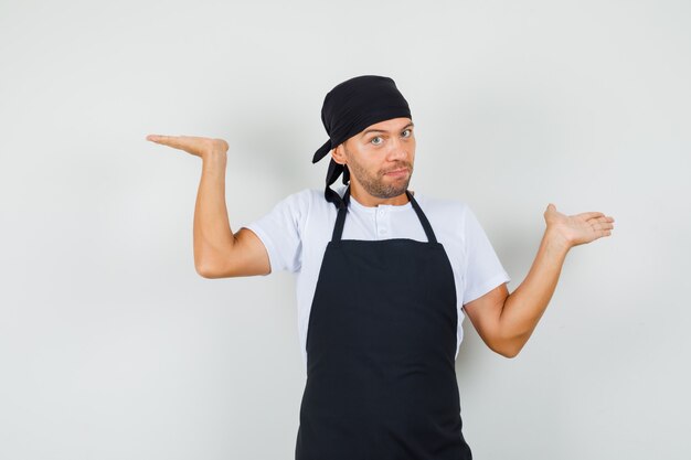 Baker man in t-shirt, apron making scales gesture