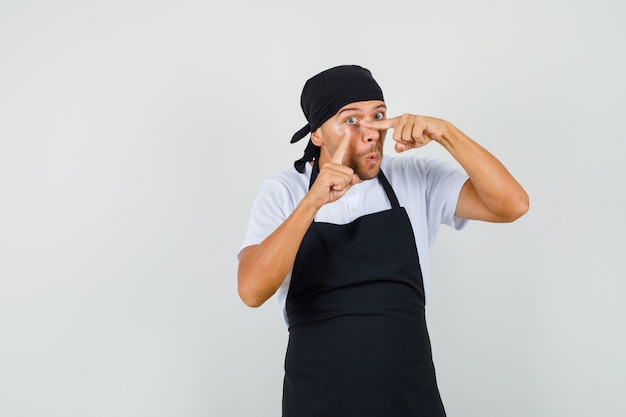 Uomo panettiere in maglietta, grembiule puntato sulla palpebra