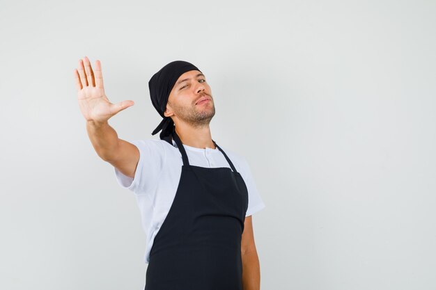 Free photo baker man in t-shirt, apron showing stop gesture and looking confident