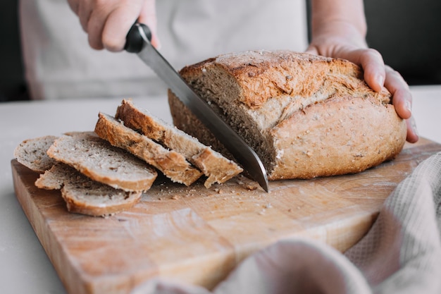 Mano del panettiere che affetta una pagnotta di pane fresco con un coltello