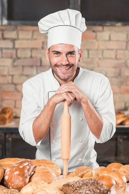 Free photo baker standing behind the table with variety of baked breads