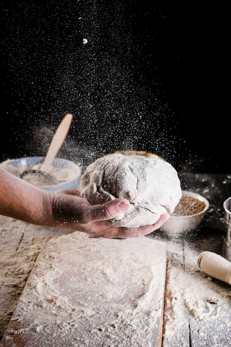 Free Photo bakers sprinkling flour over the knead dough