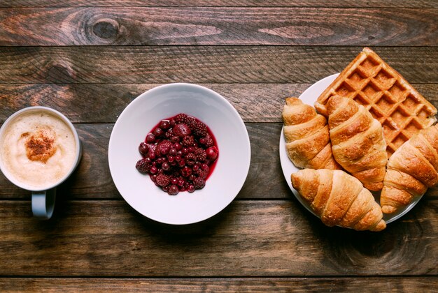 Bakery on plate near cup of drink and jam