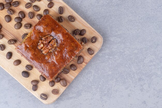 Free photo bakhlava and coffee beans on a wooden board on marble table.