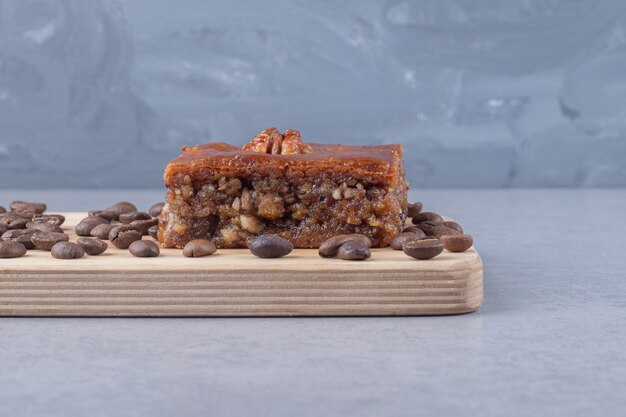 Bakhlava and coffee beans on a wooden board on marble