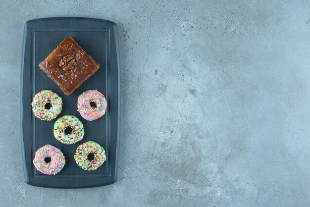 Bakhlava and donuts on a navy board on marble surface