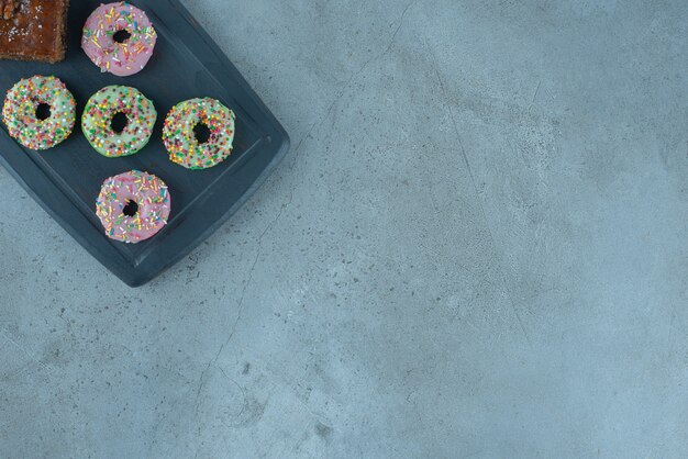 Free photo bakhlava and donuts on a navy board on marble surface