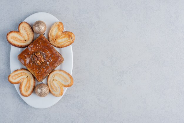 A bakhlava and flaky cookies on a platter with a bauble on marble surface