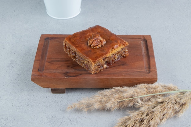 Free photo bakhlava on a small board next to a bundle of feather grass stalks on marble background.