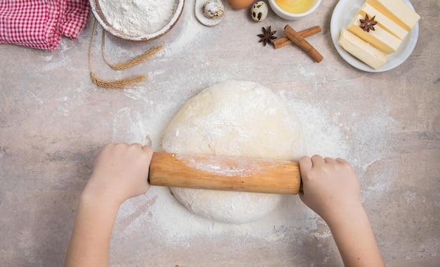 Baking cooking food ingredients child hands roll out the dough with a rolling pin on a silicone mat Premium Photo