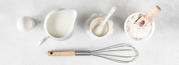 Baking ingredients egg flour sugar milk and kitchen tools on a white background with space to copy