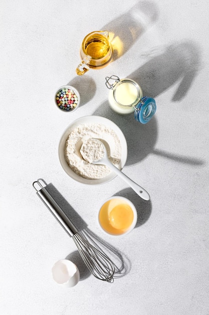 Foto gratuita ingredienti per la cottura farina uova sbatti burro e latte su uno sfondo di cemento bianco concetto di cottura