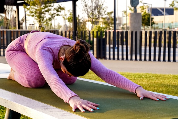 Foto gratuita donna sportiva di balasana che fa allungando yoga in parco